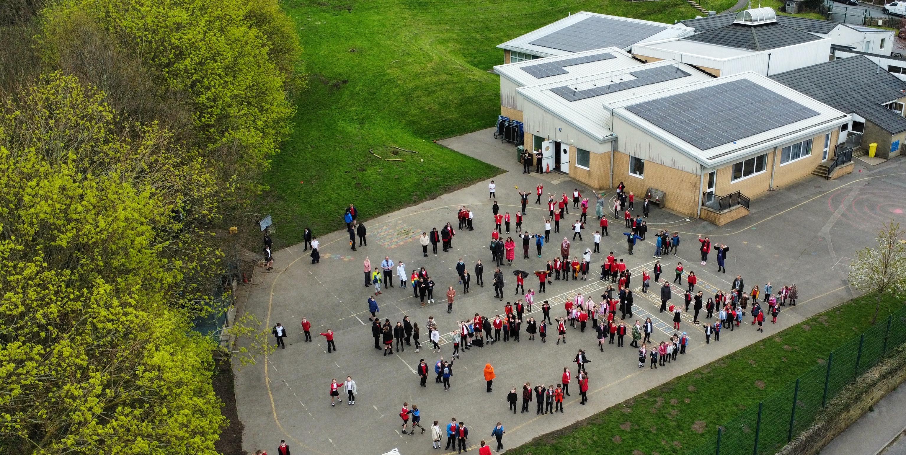 Excited children outside a school look to the sky